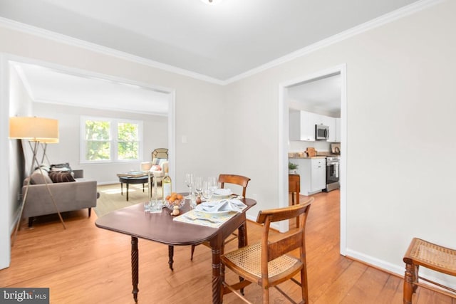 dining room featuring ornamental molding, light wood-style flooring, and baseboards