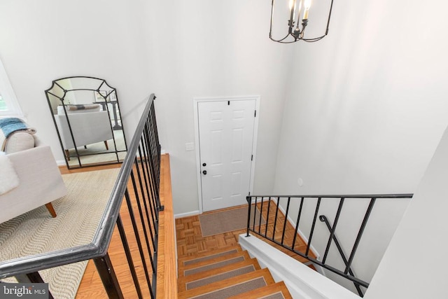 stairway with a chandelier, baseboards, and a high ceiling