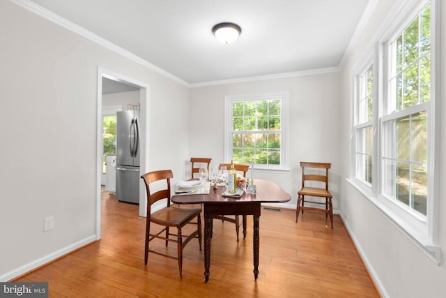 dining area with light wood-type flooring, crown molding, and baseboards