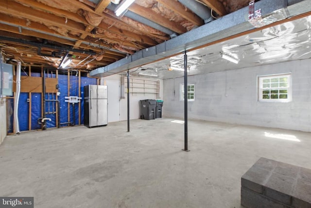 below grade area with freestanding refrigerator and healthy amount of natural light