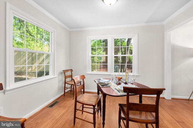 dining room with light wood finished floors, crown molding, and baseboards
