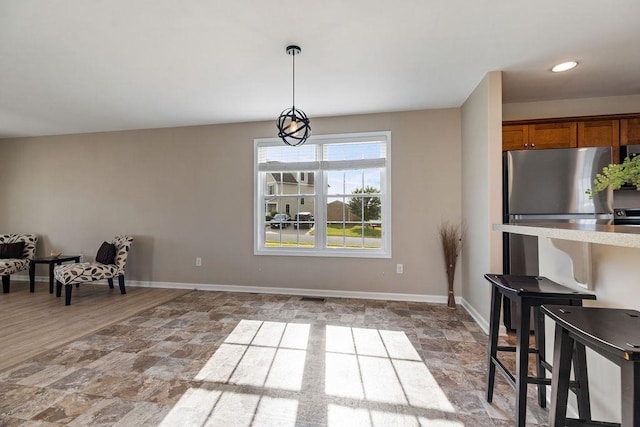 43 Upland Ct, Stuarts Draft, VA 24477 - kitchen with freestanding refrigerator, brown cabinets, hanging light fixtures, and light stone finish flooring