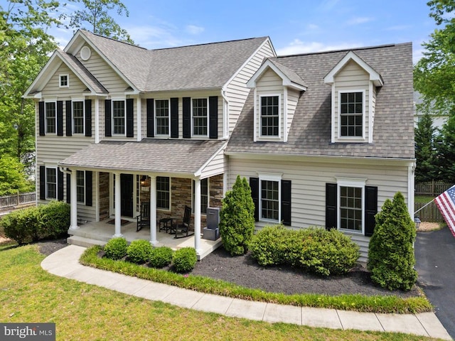 view of front of house with fence, a shingled roof, and a porch