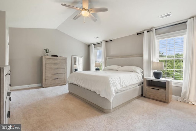 bedroom with lofted ceiling, multiple windows, light colored carpet, baseboards, and a ceiling fan