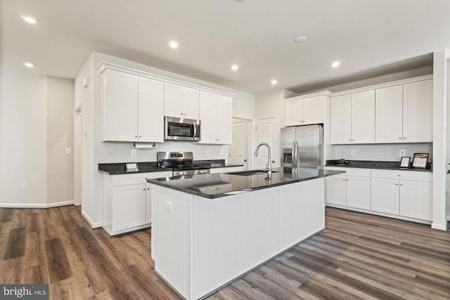6520 Wild Orchid Ct, Fredericksburg, VA 22407 - kitchen with appliances with stainless steel finishes, a sink, a kitchen island with sink, dark countertops, and white cabinets