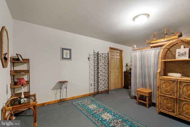 bedroom featuring finished concrete flooring and baseboards