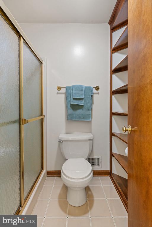 full bathroom with baseboards, a shower with shower door, and toilet