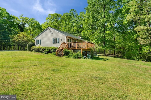 rear view of house featuring a wooden deck, stairway, and a lawn