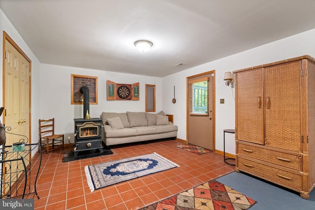 living area featuring a wood stove, tile patterned flooring, and baseboards
