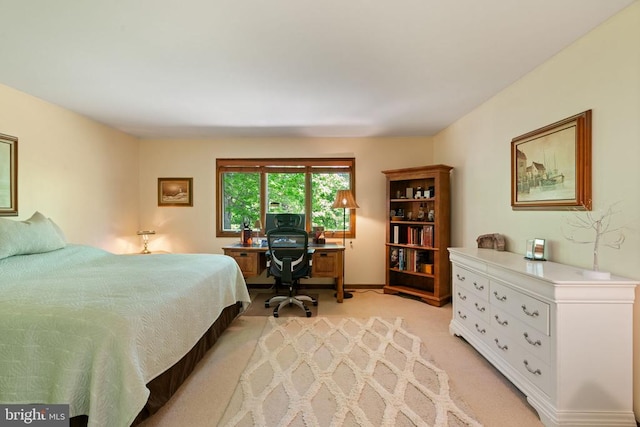 bedroom with light colored carpet and an office area