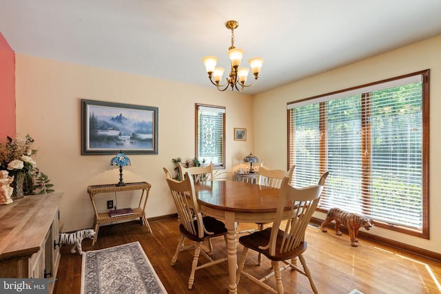 dining room with a chandelier, wood finished floors, and baseboards