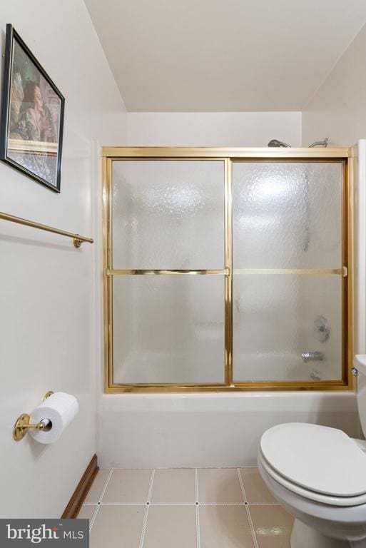 bathroom featuring toilet and bath / shower combo with glass door