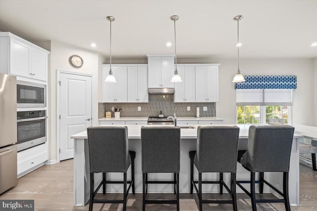 11326 Oakville Ln, Spotsylvania, VA 22551 - kitchen with stainless steel appliances, light countertops, under cabinet range hood, tasteful backsplash, and white cabinetry