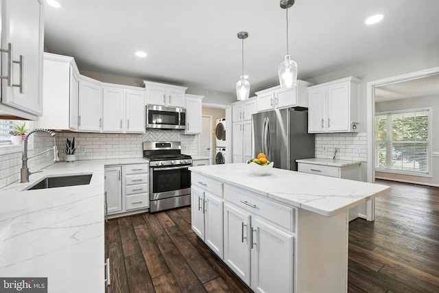 6205 Patrician Ct, Fredericksburg, VA 22407 - kitchen featuring appliances with stainless steel finishes, stacked washer and clothes dryer, tasteful backsplash, white cabinetry, and dark wood-type flooring