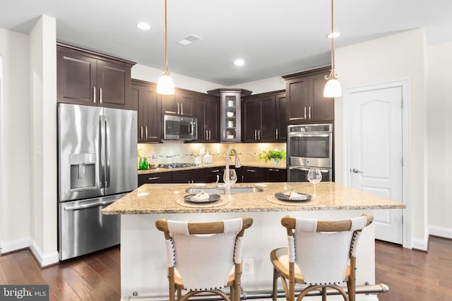 kitchen featuring stainless steel appliances, dark wood-style flooring, a sink, dark brown cabinets, and backsplash