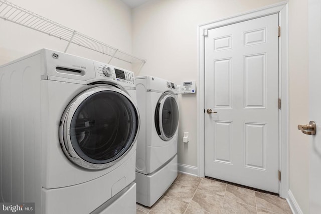 laundry area with laundry area, light tile patterned floors, baseboards, and separate washer and dryer