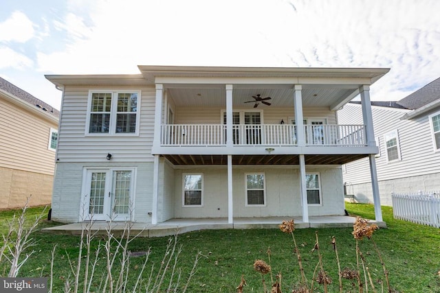 back of house with a ceiling fan, a patio area, a lawn, and a balcony