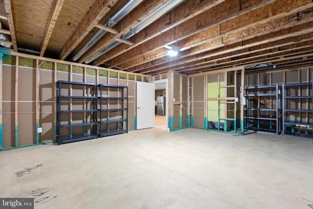 unfinished basement with freestanding refrigerator