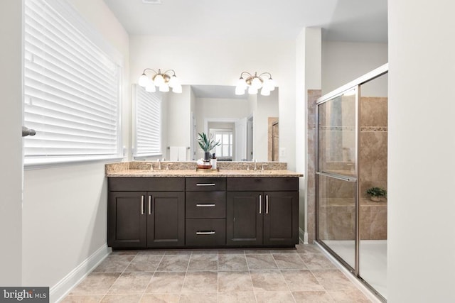 full bath with a sink, a shower stall, baseboards, and double vanity