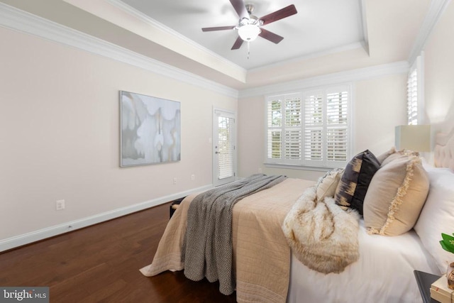 bedroom with crown molding, a raised ceiling, dark wood finished floors, and baseboards