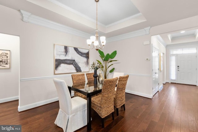 dining area featuring baseboards, a raised ceiling, wood-type flooring, crown molding, and a chandelier