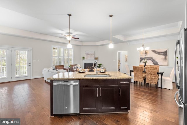 kitchen featuring dark wood finished floors, a tray ceiling, stainless steel appliances, a fireplace, and a sink