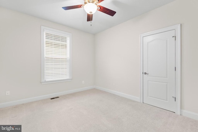 carpeted empty room with a ceiling fan, visible vents, and baseboards