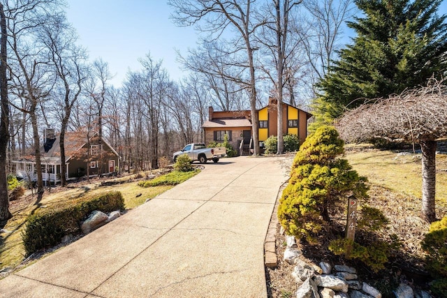 exterior space with concrete driveway and a chimney