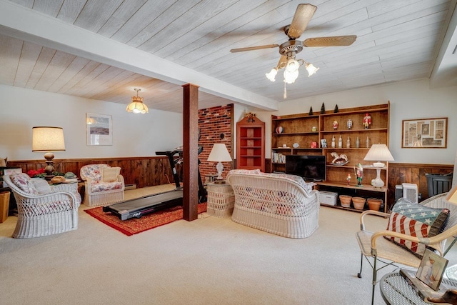 living area with a ceiling fan, wood walls, wainscoting, and carpet