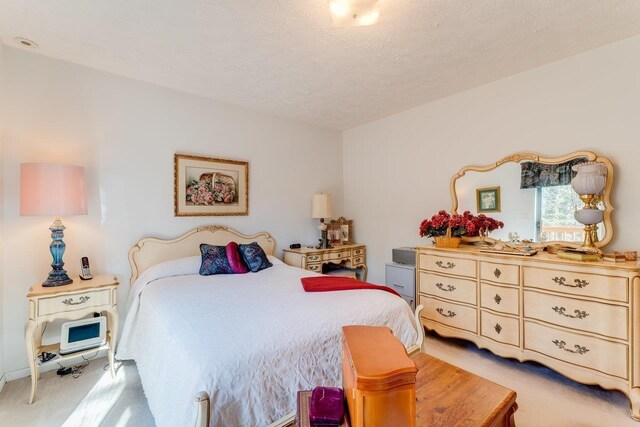 bedroom featuring light carpet and a textured ceiling