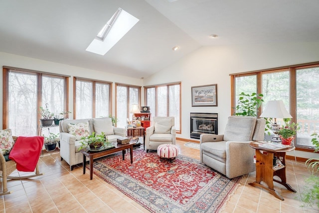 living area featuring a glass covered fireplace, light tile patterned flooring, a skylight, and high vaulted ceiling