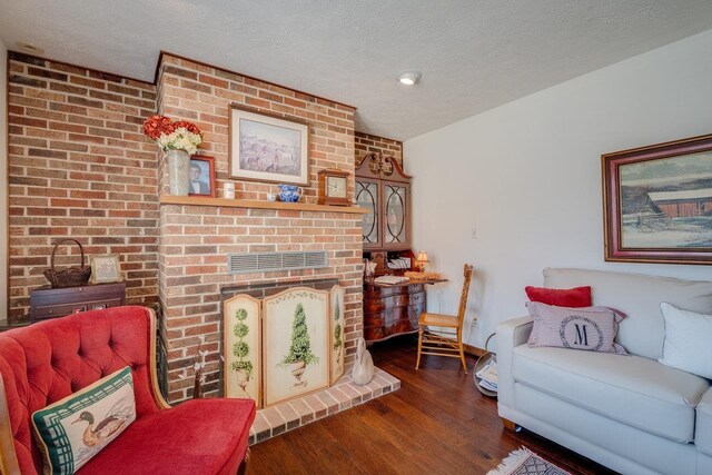 living area with a fireplace, a textured ceiling, and wood finished floors