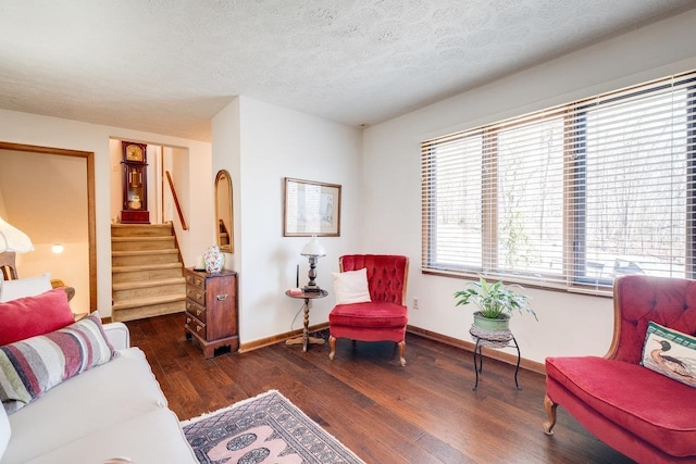 living area with baseboards, stairway, a textured ceiling, and wood finished floors