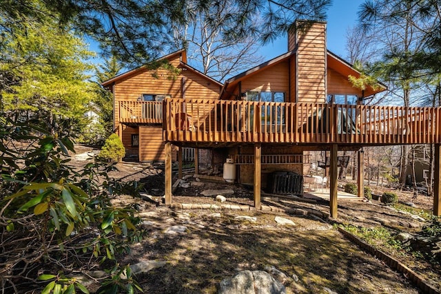 rear view of property featuring central AC unit, a chimney, and a wooden deck