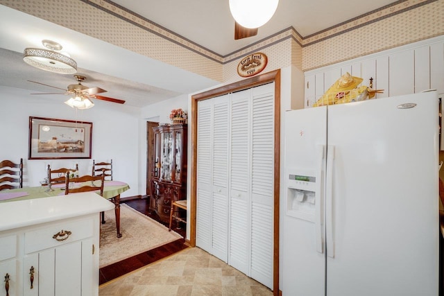 kitchen featuring white cabinets, light countertops, white refrigerator with ice dispenser, and a ceiling fan