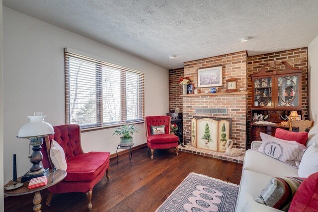 living area featuring hardwood / wood-style floors, a brick fireplace, and a textured ceiling