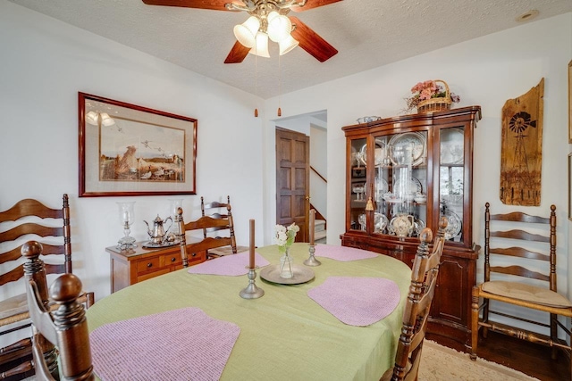 dining room with a ceiling fan, stairs, and a textured ceiling