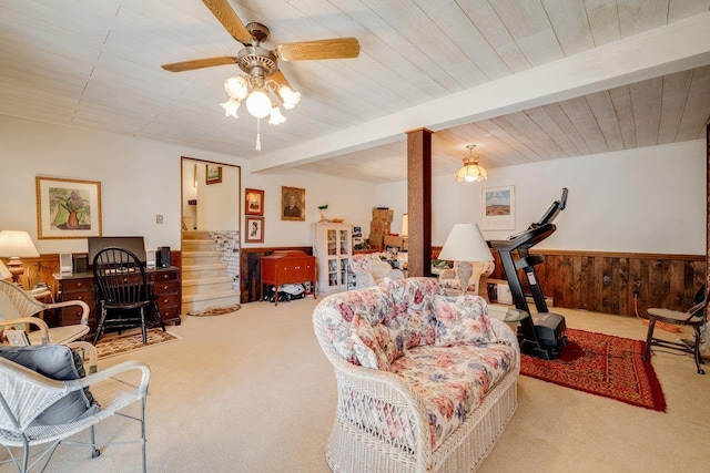 carpeted living area featuring a wainscoted wall, beam ceiling, wood walls, and ceiling fan