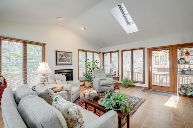 living room featuring light tile patterned floors, lofted ceiling with skylight, and a glass covered fireplace