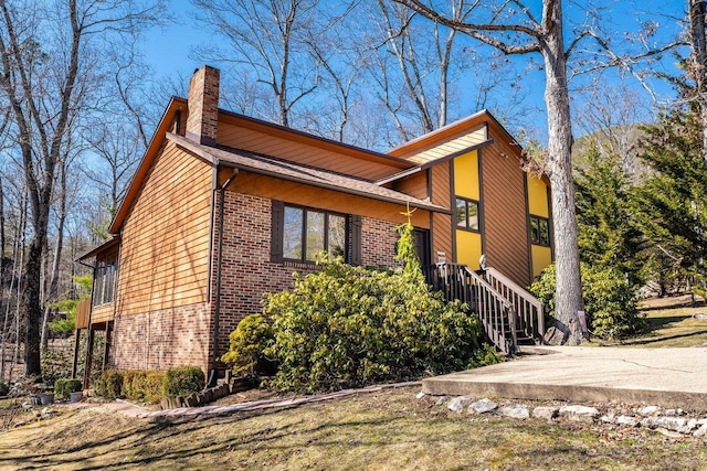 view of front of home featuring a chimney, stairs, and brick siding