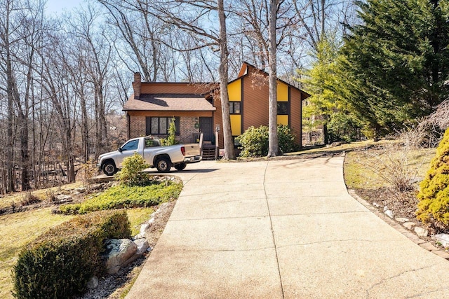 exterior space with brick siding, driveway, and a chimney