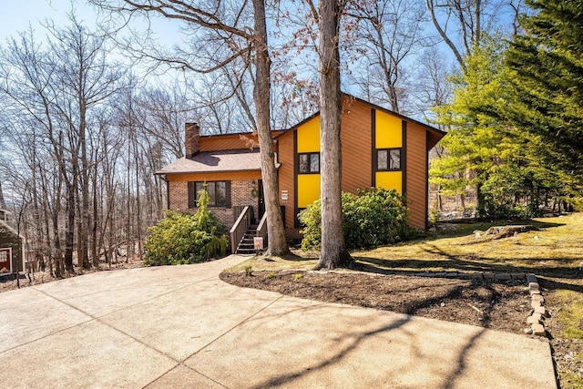 view of front facade featuring brick siding, stairs, and a chimney