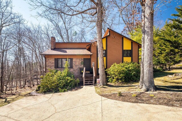view of front of property featuring brick siding, a shingled roof, and a chimney