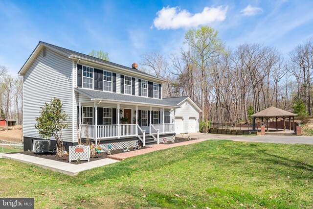 view of front of home with covered porch, a gazebo, a front yard, a chimney, and cooling unit