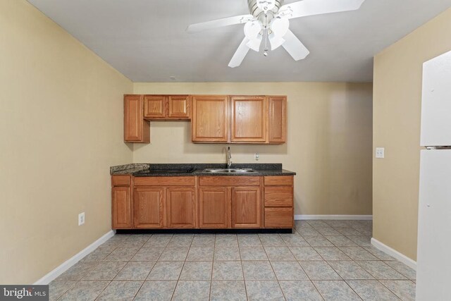 kitchen featuring a sink, ceiling fan, baseboards, and freestanding refrigerator
