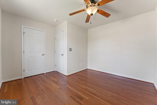 unfurnished bedroom with wood finished floors, baseboards, and a ceiling fan