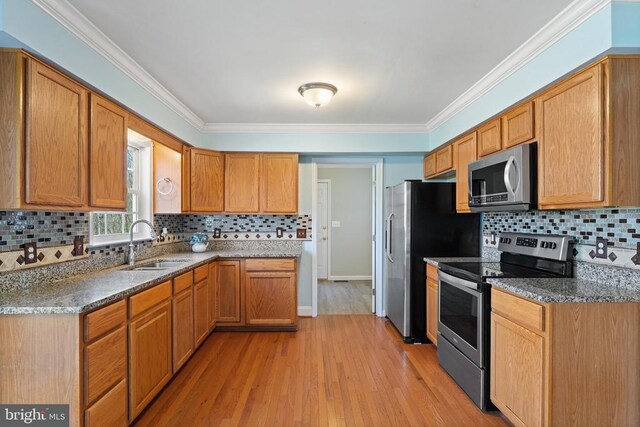 kitchen with stainless steel appliances, a sink, tasteful backsplash, light wood-style floors, and ornamental molding
