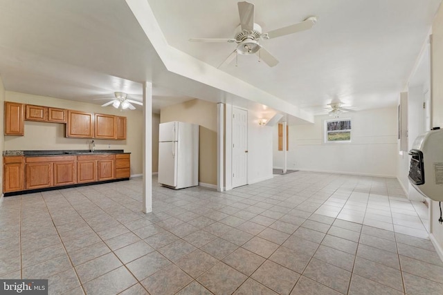 unfurnished living room featuring a ceiling fan, light tile patterned floors, baseboards, and heating unit