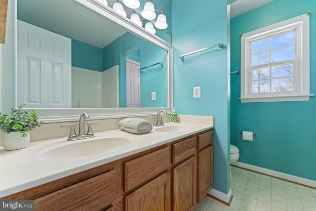 full bathroom featuring toilet, double vanity, and baseboards