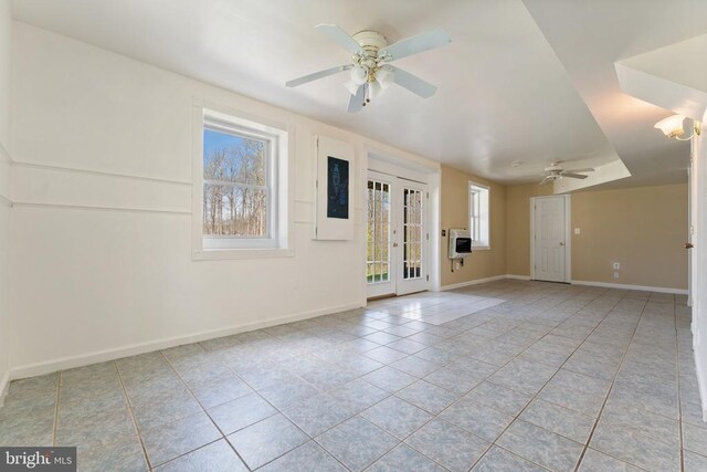 empty room featuring ceiling fan, tile patterned flooring, heating unit, and baseboards
